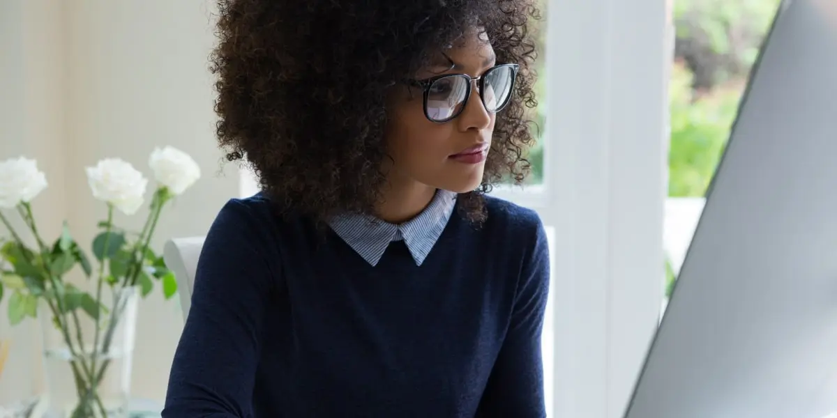 A marketing manager sitting at a desk working on a computer, putting together a multichannel marketing strategy