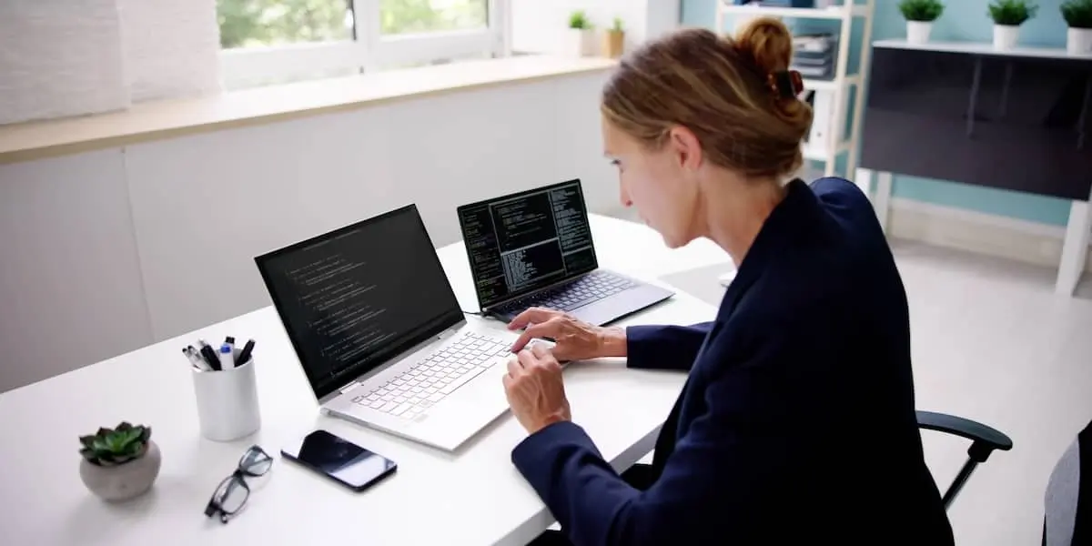 analytics engineering is a growth area An analytics engineer sits in a bright home office with two laptops of code.